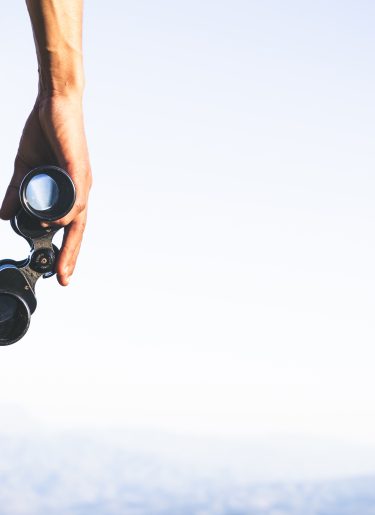 Tourist is holding through binoculars on sunny cloudy sky from m