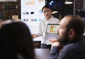 Woman presenting charts and data on a board during a meeting, Korean performance bonuses