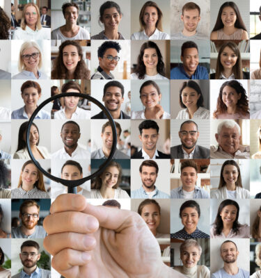 Hr holding magnifying glass choosing african candidate among people faces