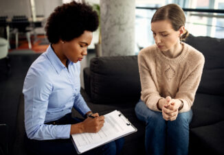 Black female counselor taking notes while having conversation with another woman