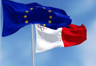 Flags of Malta and the European Union waving in the wind on a clear day.