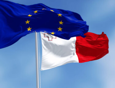 Flags of Malta and the European Union waving in the wind on a clear day.