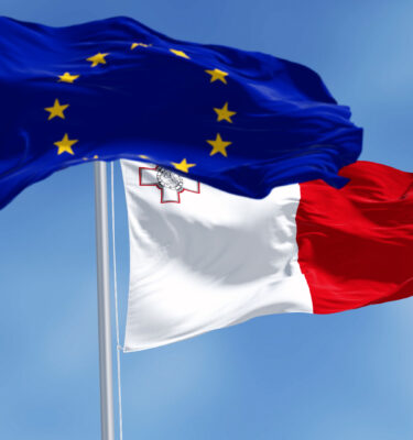 Flags of Malta and the European Union waving in the wind on a clear day.