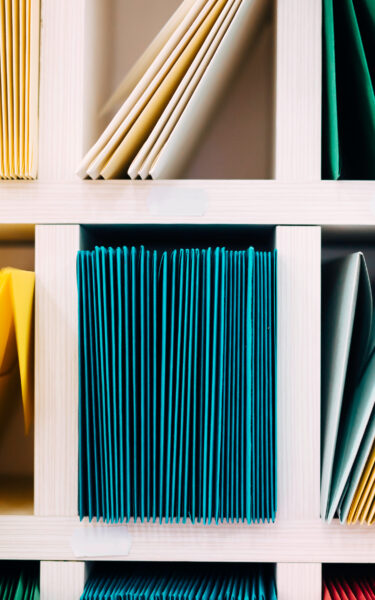 Image of Multicolored mail envelopes arranged on a shelf by color and type categories. For the webinar: Categorisation – defining categories of workers and work of equal value