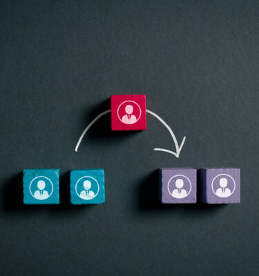 Wooden employee icon moving between two teams, representing workforce mobility, reassignment, talent transfer, organizational change and internal career transition.