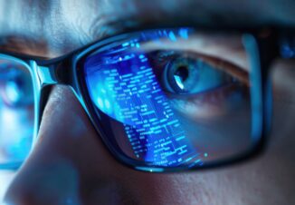 Smart glasses reflecting digital data stream over eye of man working in dark blue lighting.