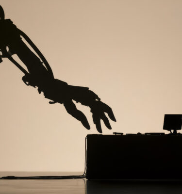 Silhouette of a man facing a giant robotic arm at a desk
