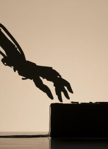 Silhouette of a man facing a giant robotic arm at a desk
